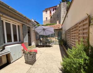 eine Terrasse mit einem Sonnenschirm, einem Tisch und Stühlen in der Unterkunft Maisonnette studio bas Suquet, 200m plages, 700m palais, au calme in Cannes