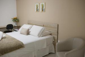 a bedroom with a white bed and a chair at Costa do Rio Hotel in Petrolina +7 photos