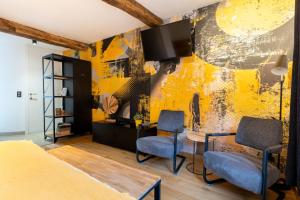 a room with two chairs and a tv on a yellow wall at Ardenne BnB gîte urbain avec terrasse in Marche-en-Famenne