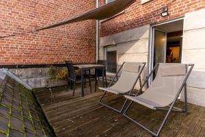 a patio with chairs and a table and a brick wall at Ardenne BnB gîte urbain avec terrasse in Marche-en-Famenne