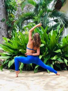 a woman doing a yoga pose on the beach at Zarafa House in Diani Beach