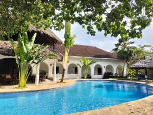 une villa avec une piscine en face d'une maison dans l'établissement Zarafa House, à Diani Beach