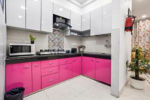 eine Küche mit rosa Schränken und einer Mikrowelle in der Unterkunft Homlee Villa Apartment with kitchen in East Delhi- Ghaziabad in Ghaziabad