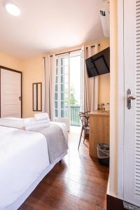 a bedroom with a bed and a desk and a television at Pousada Catedral in Petrópolis