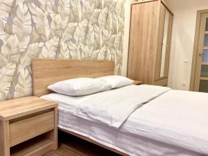 Schlafzimmer mit einem Bett mit einem Kopfteil aus Holz in der Unterkunft 2-кімн Сучасні апартаменти у центрі міста in Poltawa