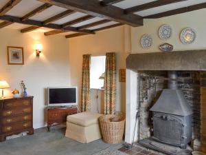 a living room with a fireplace and a television at Lilac Cottage in Sinnington