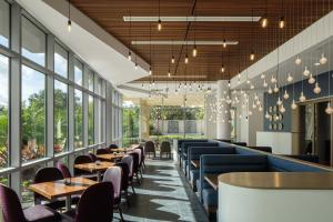 a restaurant with tables and chairs and windows at The Celeste Hotel, Orlando, a Tribute Portfolio Hotel in Orlando