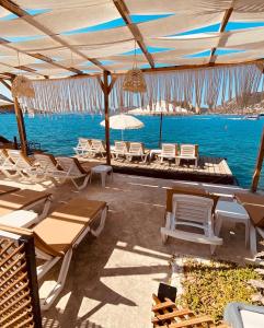 un patio con sillas, mesas y el océano en Seyyah Suites Bozburun, en Marmaris