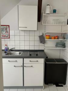 een keuken met witte kasten en een wastafel bij Kleines Apartment in Mönchengladbach-Neuwerk in Mönchengladbach