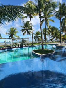 uma grande piscina com palmeiras ao fundo em Villa Oberoi pé na areia alto luxo em Santo André