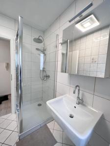 a white bathroom with a sink and a shower at Neu sanierte Einzimmerwohnung in Bad Nauheim