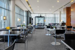 un restaurante con mesas, sillas y ventanas en AC Hotel Guadalajara by Marriott, Spain, en Guadalajara