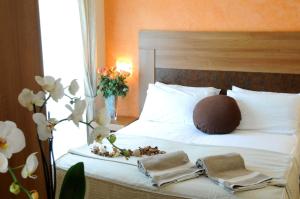 Hotel I Due Cigni في مونتيبولسيانو: غرفة نوم بسرير عليها مناشف وزهور