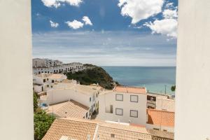 a view of the roofs of buildings and the ocean at apartment with amazing sea view in Burgau