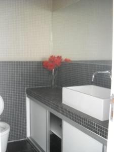 a bathroom with a sink and red flowers on a counter at apartment with amazing sea view in Burgau