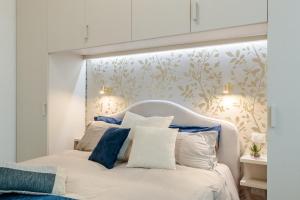 a bedroom with a white bed with blue and white pillows at Casa Versilia Style in Viareggio