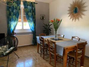 una mesa de comedor con sillas y un jarrón de flores. en gite des huskys en Tonnay-Charente
