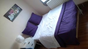 a bedroom with a bed with purple and white sheets and pillows at Petite maison indépendante avec terrasse privée in Montmorillon