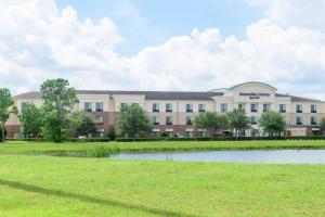 a large building with a pond in front of it at SpringHill Suites Houston Pearland in Pearland