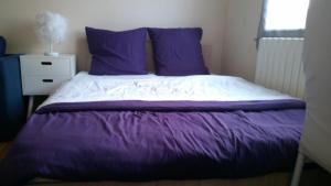 a bed with purple and white sheets and a window at Petite maison indépendante avec terrasse privée in Montmorillon