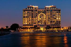 a large building with an arch lit up at night at Ajman Saray, a Luxury Collection Resort, Ajman in Ajman 