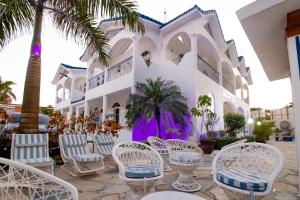 un complejo con sillas blancas y palmeras en Hotel Villa Capri, en Boca Chica