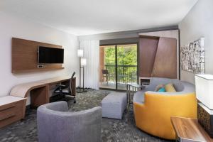 um quarto de hotel com uma secretária e uma sala de estar em Courtyard Lafayette Airport em Lafayette