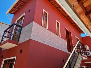 czerwony dom ze schodami na boku w obiekcie Suíte na vila de Praia do Forte w mieście Praia do Forte