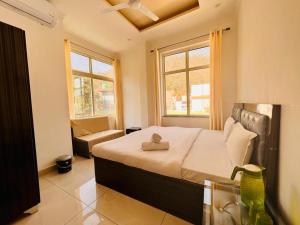 a bedroom with a bed and a couch and two windows at Hotel Amrit Bliss in Rishīkesh