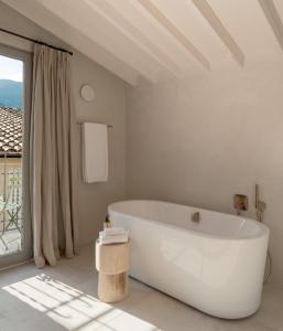 a white bathroom with a tub and a window at Can Verí Suites in Sóller