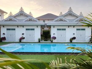 a villa with a swimming pool in front of a house at Bianco House Resort in Cha Am