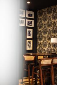 une salle à manger avec une table, des chaises et un mur avec des photos dans l'établissement Churchill Hotel Bayeux Centre, à Bayeux