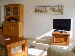 a living room with a couch and a tv on a table at Beach House in Sheringham