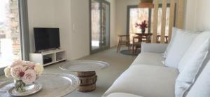 a living room with a white couch and a table with flowers at Villa Veneterra-Pool-SeaView-ConciergeServices in Koundouros