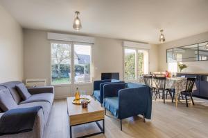 a living room with blue chairs and a table at Maison vélo piscine tennis in Deauville