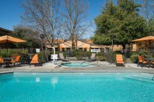 a swimming pool with chairs and a table and umbrella at Courtyard by Marriott Vacaville in Vacaville