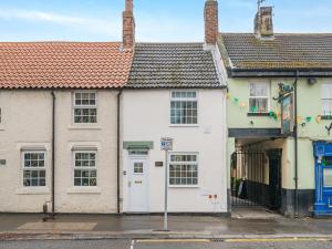 a white house with a red roof in a street at The Tipsy Bee At 143, in Guisborough