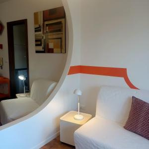 Habitación con cama blanca y espejo. en Appartamento Velocipede en Cervignano del Friuli