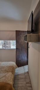 1 dormitorio con 1 cama y TV en la pared en Departamento Costa Paz en Villa Carlos Paz