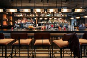 a bar with four stools in front of a counter at Moxy Louisville Downtown in Louisville