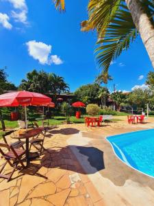 un patio con mesas y sombrillas junto a una piscina en Quintal das Estrelas en São Pedro