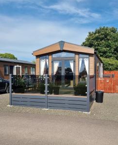 a greenhouse with a wooden roof and a fence at Kimadalyn in Forfar