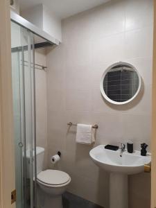 a bathroom with a toilet and a sink and a mirror at El piso de Valle-Inclán in Pontevedra