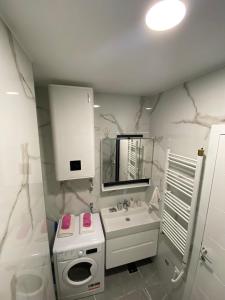 a white bathroom with a sink and a mirror at Apartman Cristal LUX in Trebinje