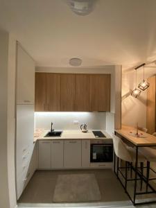 a kitchen with white cabinets and a table with a sink at Apartman Cristal LUX in Trebinje