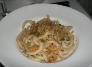 a white plate of pasta with onions and seasoning at Hotel I Due Cigni in Montepulciano