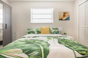 a bedroom with a bed with a green leaf printed bedspread at Sleeps 8, Havana Nights in Miami in Miami