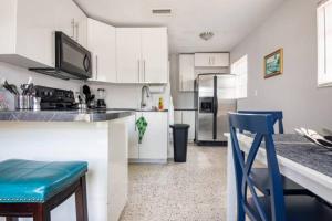 a kitchen with white cabinets and a blue stool at Sleeps 8, Havana Nights in Miami in Miami