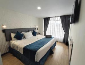 a bedroom with a large bed with blue pillows at Hotel CGH Bogota Airport in Bogotá