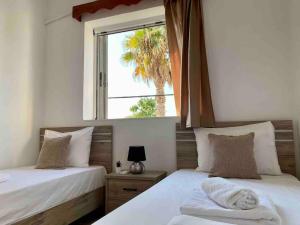 two beds in a room with a window at Elgreco Apartment, with nice view, in Kos Town "12" in Kos Town